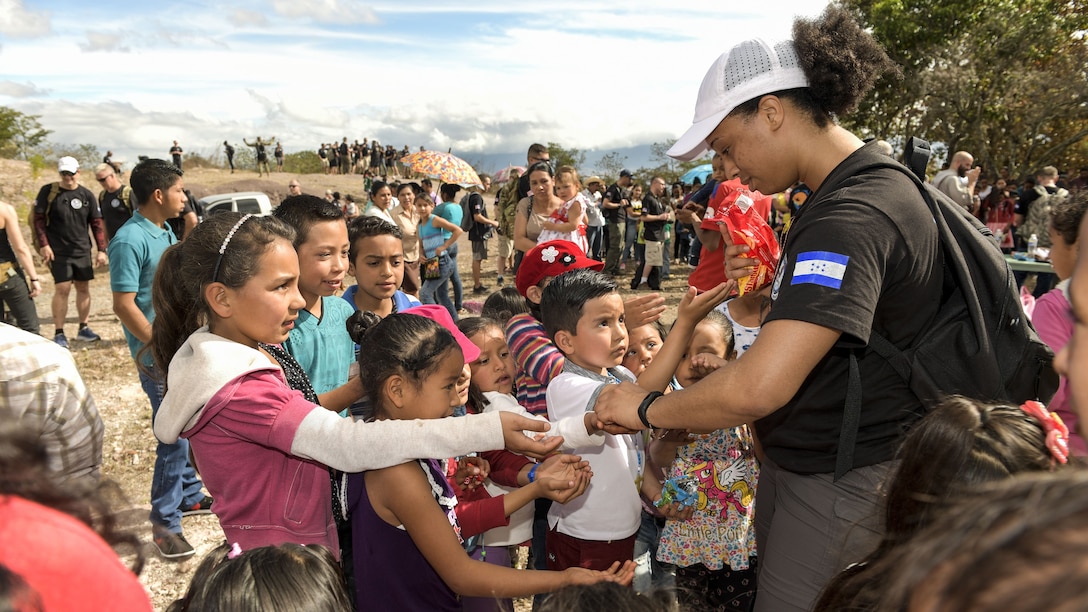 An airman hands out sweets to children in a village in Honduras.