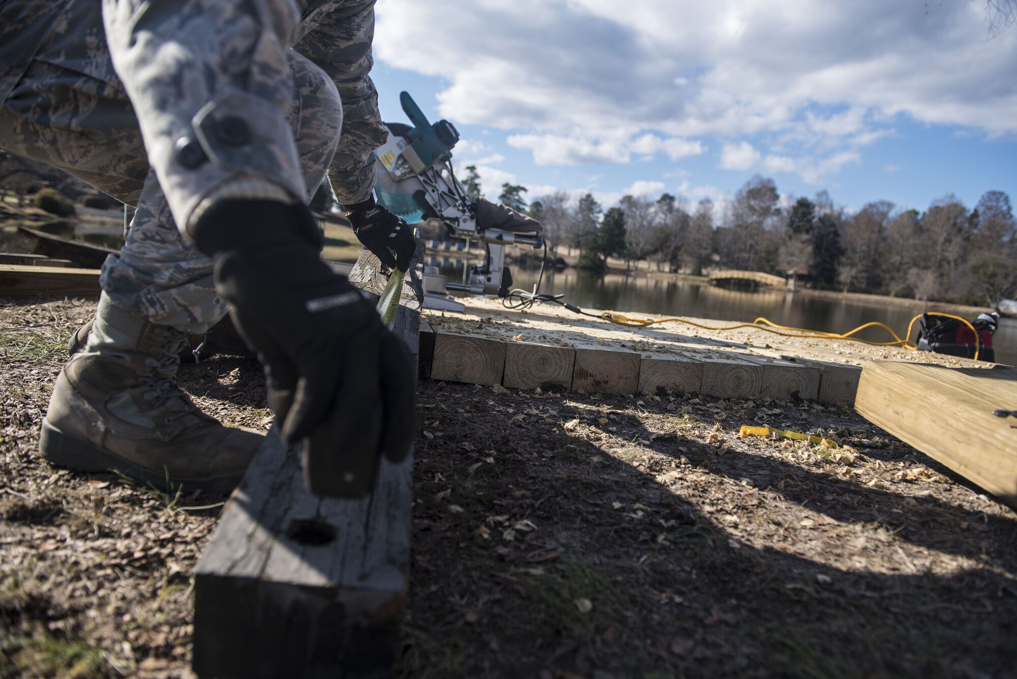 U.S. Air Force 1st Lt. Alvin Yip, 20th Civil Engineer Squadron deputy officer in charge of requirements and optimization, measures a piece of wood in front of Memorial Lake at Shaw Air Force Base, S.C., Feb. 5, 2018.