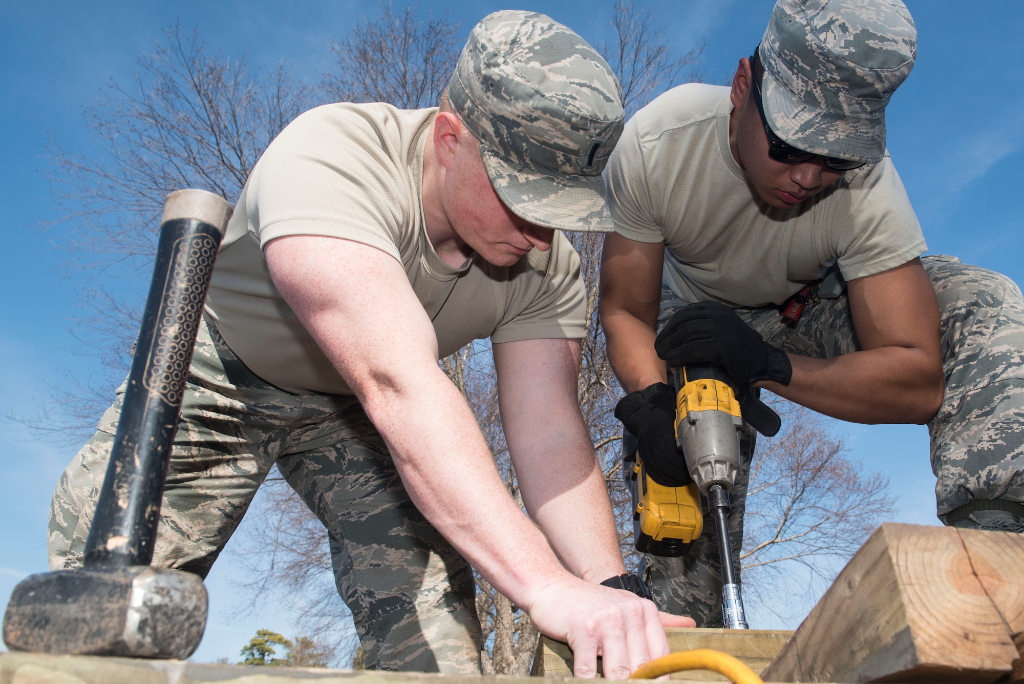 U.S. Air Force 1st Lt. Joseph Humphrey, 20th Civil Engineer Squadron (CES) deputy installation management flight commander, holds a piece of wood while Airman 1st Class Edward Balderas, 20th CES power production technician, tightens a bolt at Shaw Air Force Base, S.C., Feb. 6, 2018.