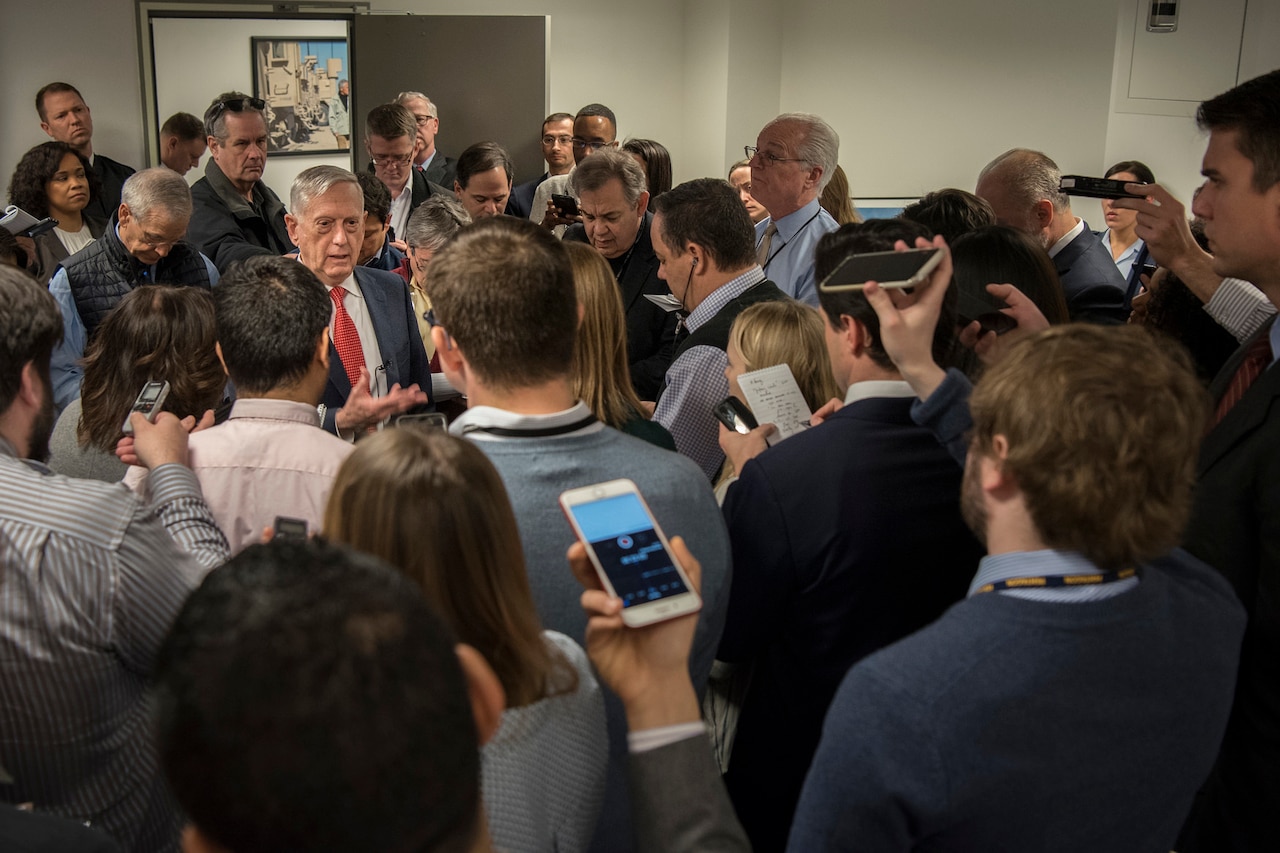 Defense Secretary James N. Mattis stands among a crowd of reporters.