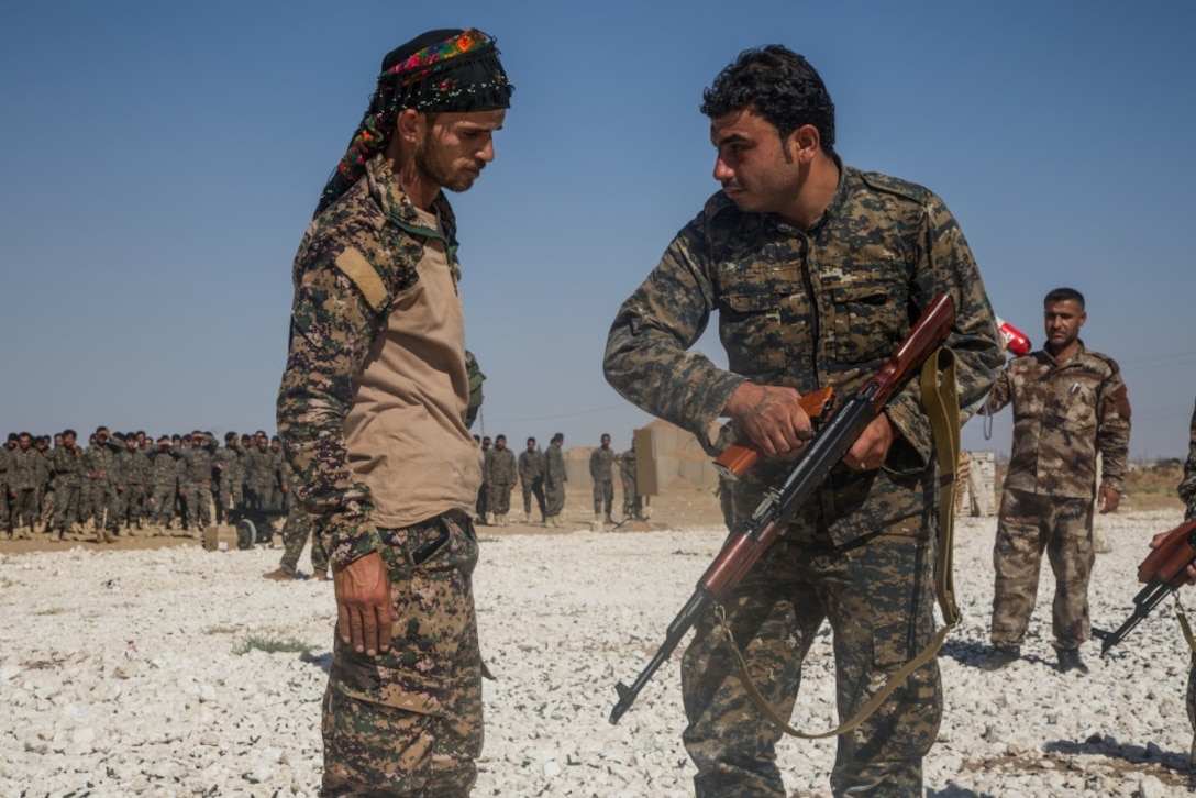 An instructor with the Syrian Democratic Forces observes as a Syrian Arab trainee clears his rifle during small-arms training in northern Syria.