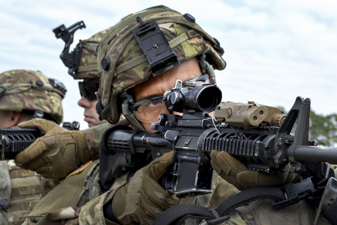 A soldier looks through his weapon's scope.