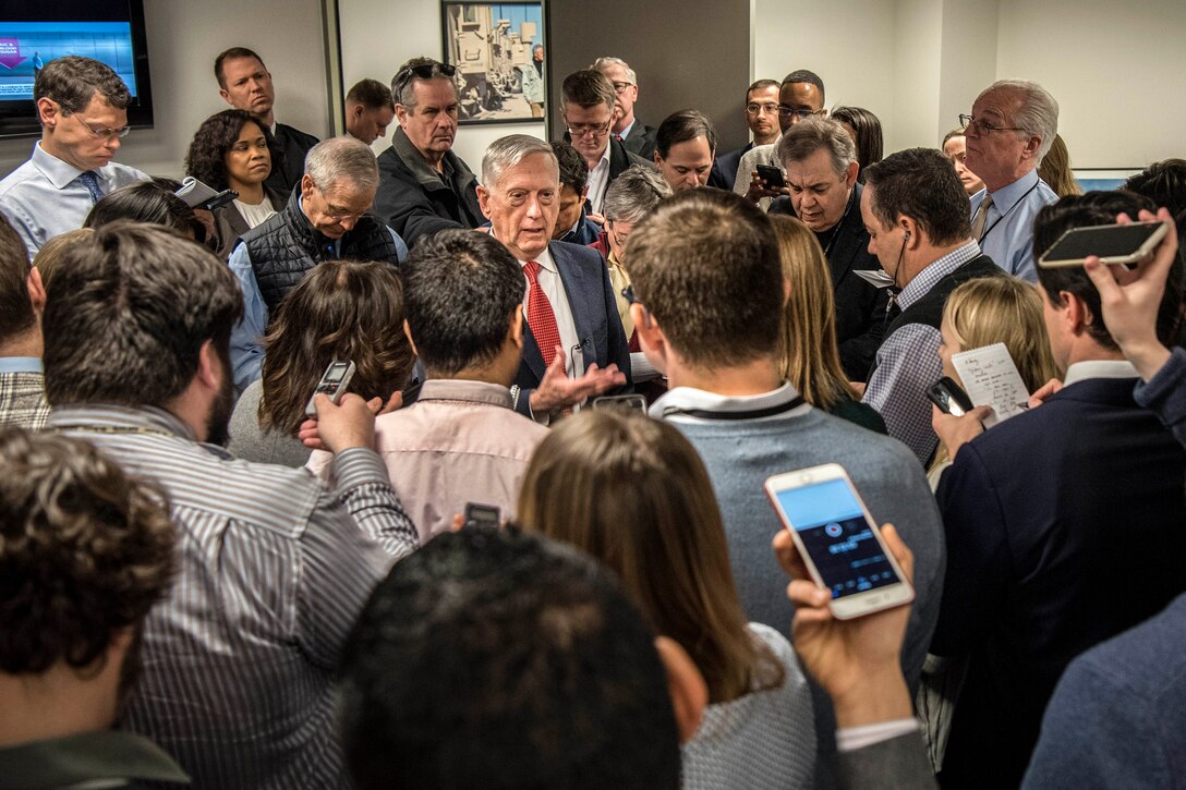 Reporters crowd around Defense Secretary James N. Mattis and hold up cell phones while he talks.