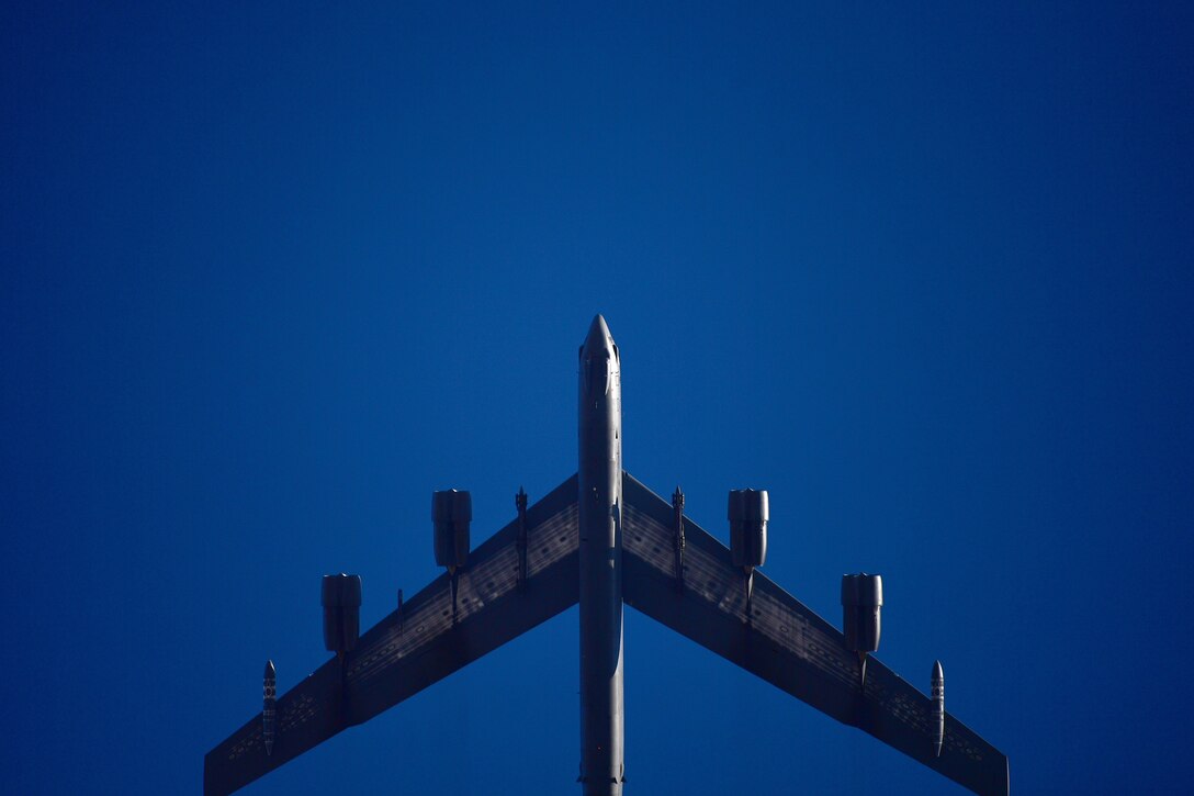 A B-52 flies in a deep blue sky.
