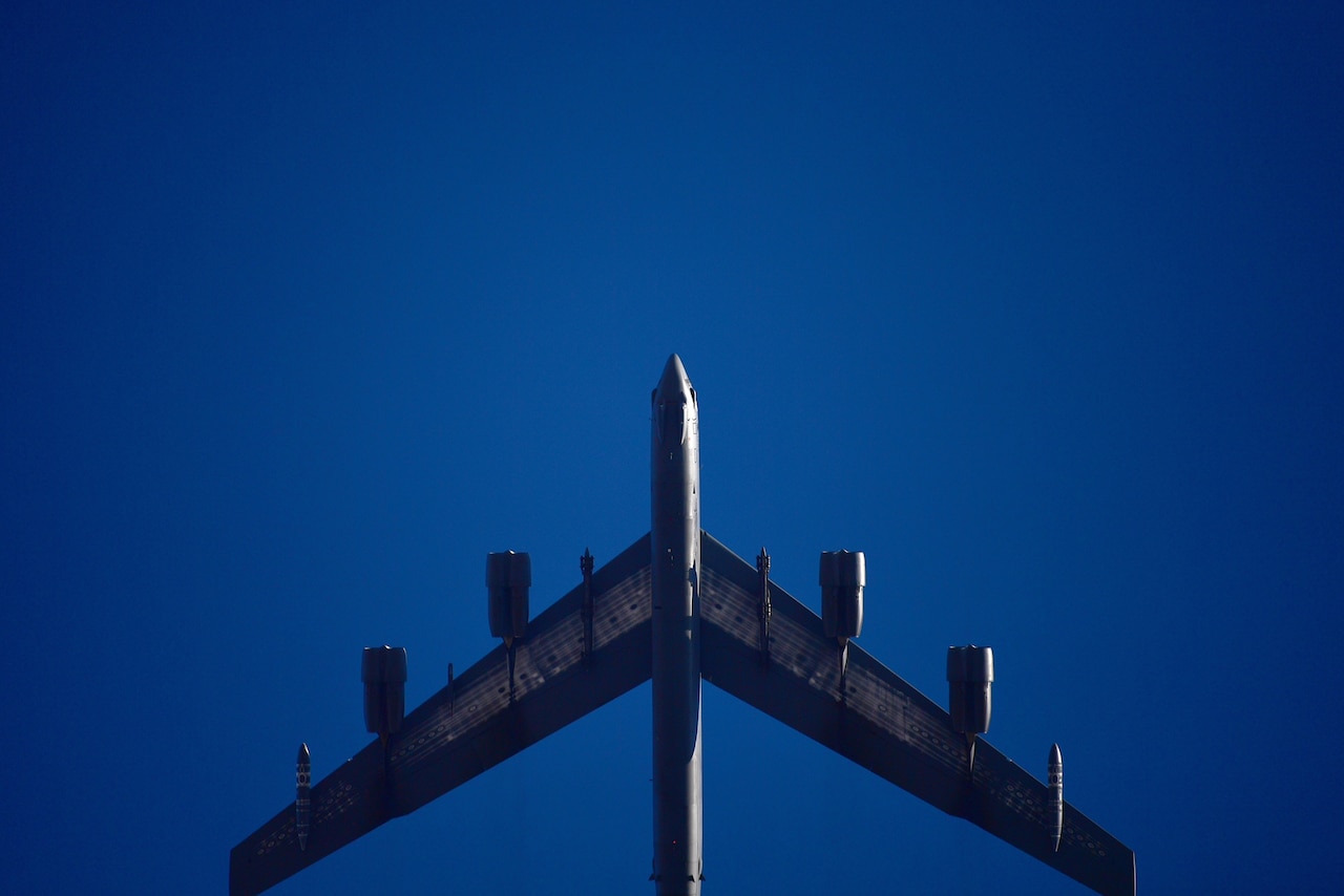 A B-52 flies in a deep blue sky.