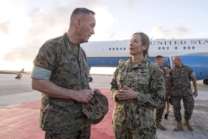 The chairman of the Joint Chiefs of Staff speaks to a Navy rear admiral near an aircraft.