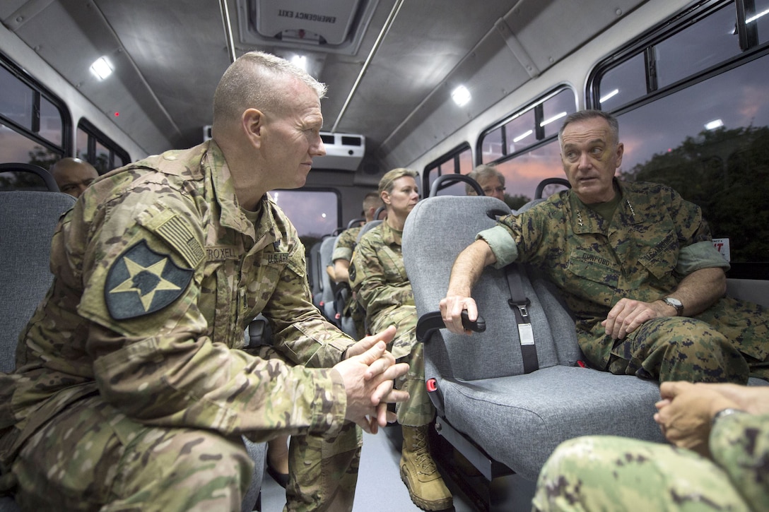 The chairman of the Joint Chiefs of Staff and other service members ride in a bus.