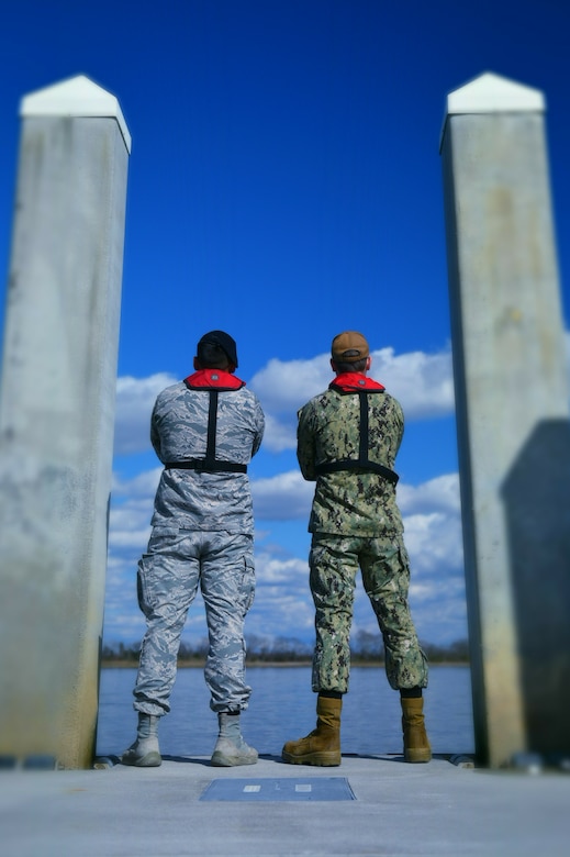 Airman 1st Class Alexander Regalado, left, 628th Security Forces Squadron patrolman, and Petty Officer 1st Class Kristopher Alphin, 628th SFS master-at-arms, stand side by side at a pier on Joint Base Charleston Naval Weapons Station, S.C. Feb 5, 2018.