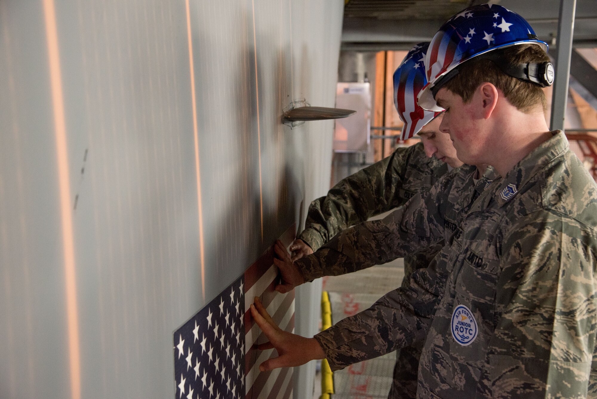 Eric Walls, Nicholas Murphy and Spencer Coleman, Polytech High School Junior ROTC cadets, place their hands on the American flag painted on a C-5M Super Galaxy’s tail Jan. 30, 2018, inside the Isochronal Maintenance Dock on Dover Air Force Base, Del. The cadets were paying homage to fallen American service members who have sacrificed their lives for the United States. (U.S. Air Force photo by Senior Airman Damien Taylor)