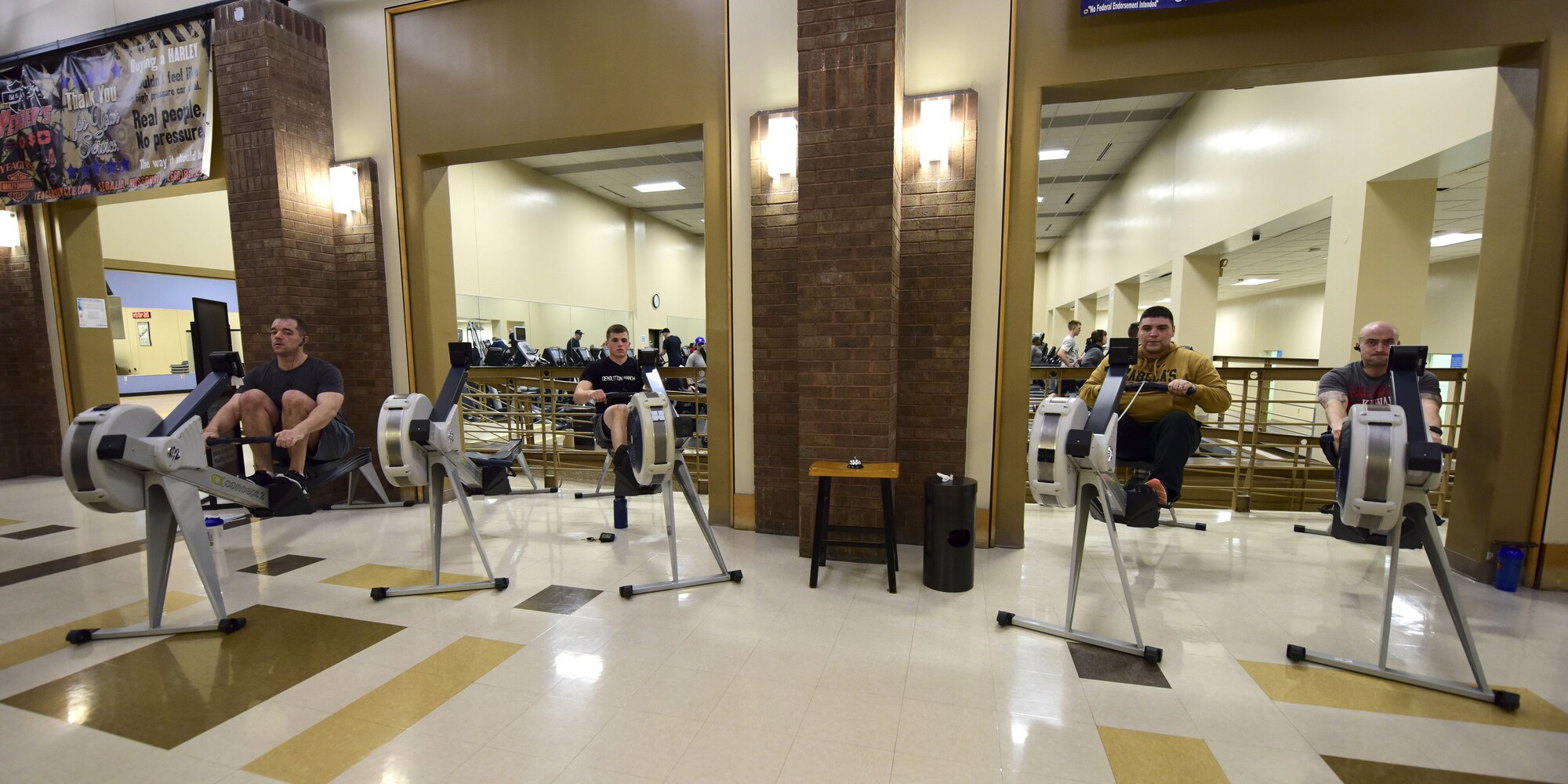 Participants of the first Base vs. Base Rowing Challenge begin rowing during the competition opening ceremony at Whiteman Air Force Base, Mo., Feb. 1, 2018. Before getting on one of the designated air rowers, participants check in with the fitness center front desk to ensure their meters are tracked.