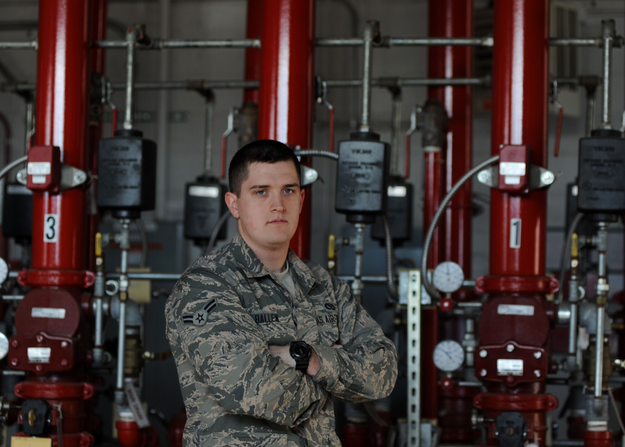 A male is pictured in front of a line of red pipes indoors.