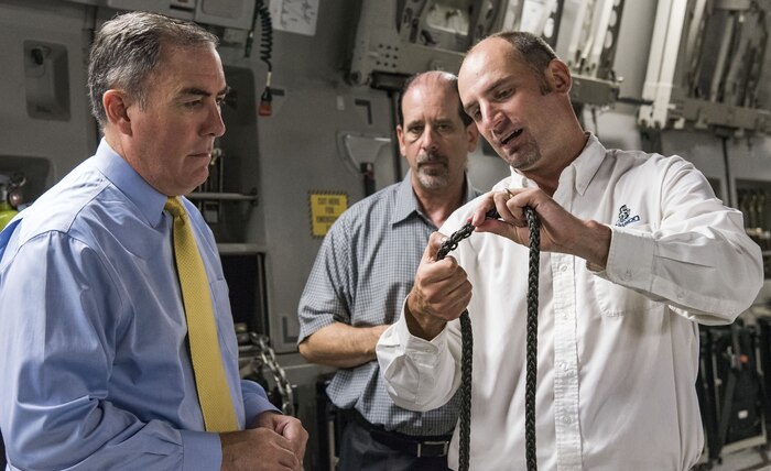 Justin Smoak, Samson Rope application engineering manager, Ferndale, Wash., right, shows Roberto Guerrero, Deputy Assistant Secretary of the Air Force for Operational Energy, Headquarters U.S. Air Force, Washington, D.C., left, and Ed Clark, AFRL aircraft programs support contractor with Concurrent Technologies Corporation, Johnstown, Pa., the weaving of the synthetic winch cable, Sept. 6, 2017, at Dover Air Force Base, Del. The proposed 280-foot synthetic winch cable weighs 14 pounds and is 83 percent lighter than the current 80 pound steel wire cable. (U.S. Air Force photo by Roland Balik)