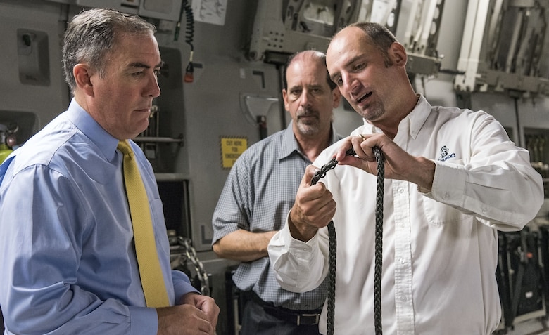 Justin Smoak, Samson Rope application engineering manager, Ferndale, Wash., right, shows Roberto Guerrero, Deputy Assistant Secretary of the Air Force for Operational Energy, Headquarters U.S. Air Force, Washington, D.C., left, and Ed Clark, AFRL aircraft programs support contractor with Concurrent Technologies Corporation, Johnstown, Pa., the weaving of the synthetic winch cable, Sept. 6, 2017, at Dover Air Force Base, Del. The proposed 280-foot synthetic winch cable weighs 14 pounds and is 83 percent lighter than the current 80 pound steel wire cable. (U.S. Air Force photo by Roland Balik)