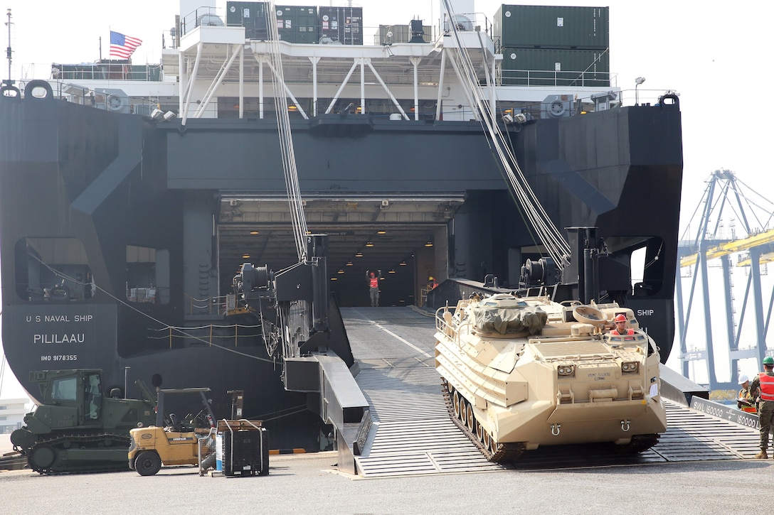 Heavy equipment rolls off the ramp of a U.S. cargo ship in Thailand.