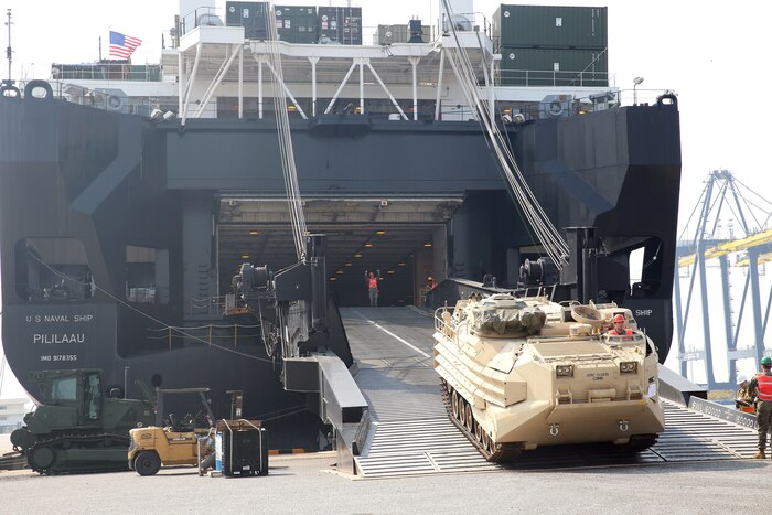 Heavy equipment rolls off the ramp of a U.S. cargo ship in Thailand.