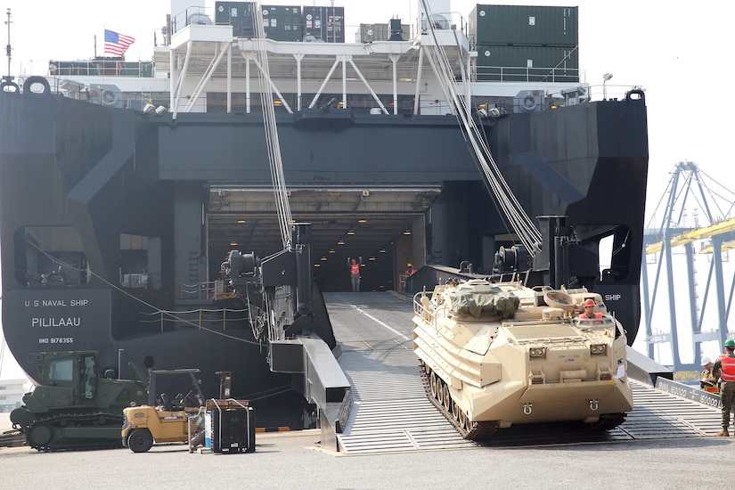 Heavy equipment rolls off the ramp of a U.S. cargo ship in Thailand.