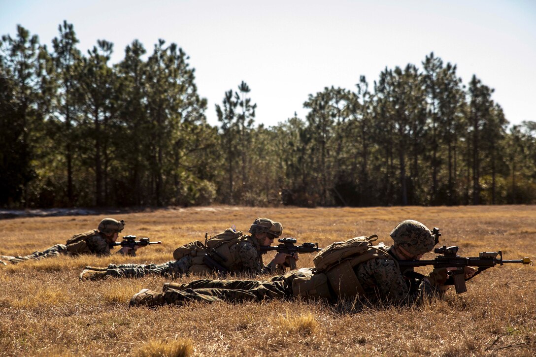 Marines and sailors lay on the ground with rifles to establish a security perimeter.
