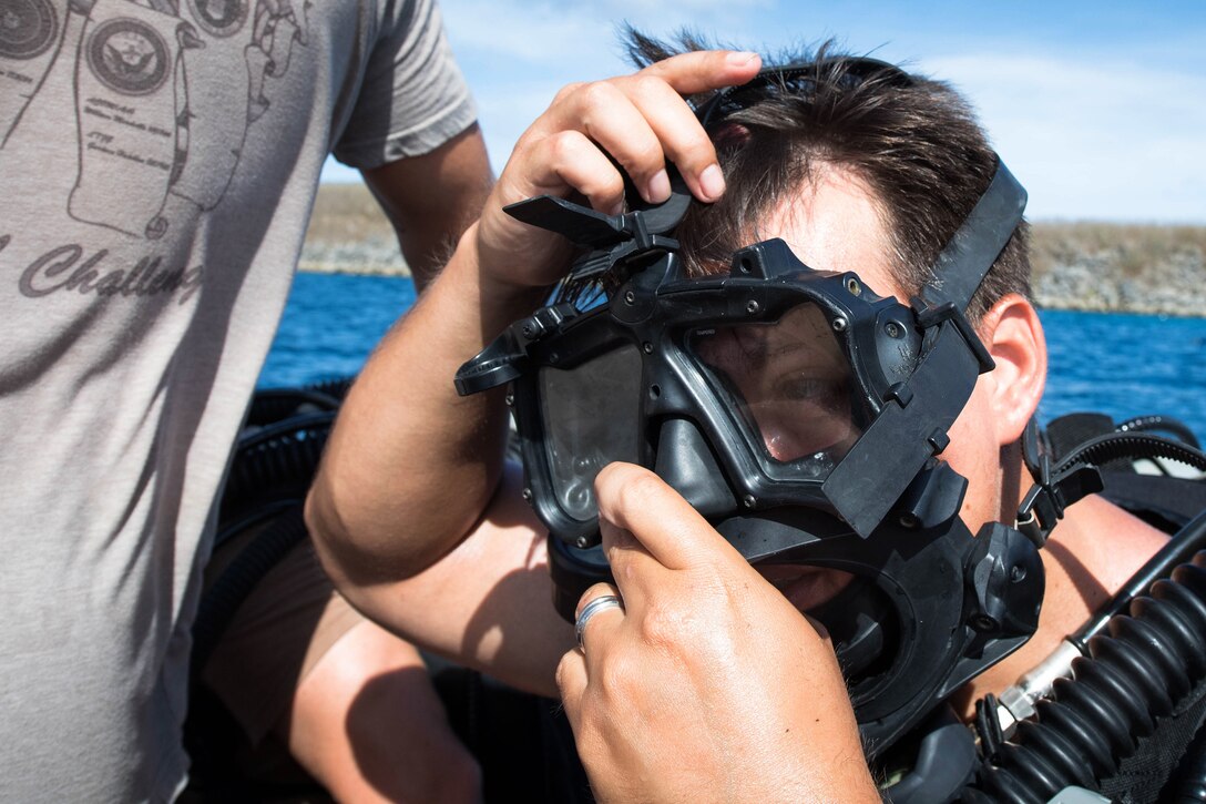 A sailor adjusts a swim mask.