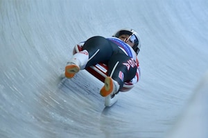 A woman in USA gear rides a luge sled.