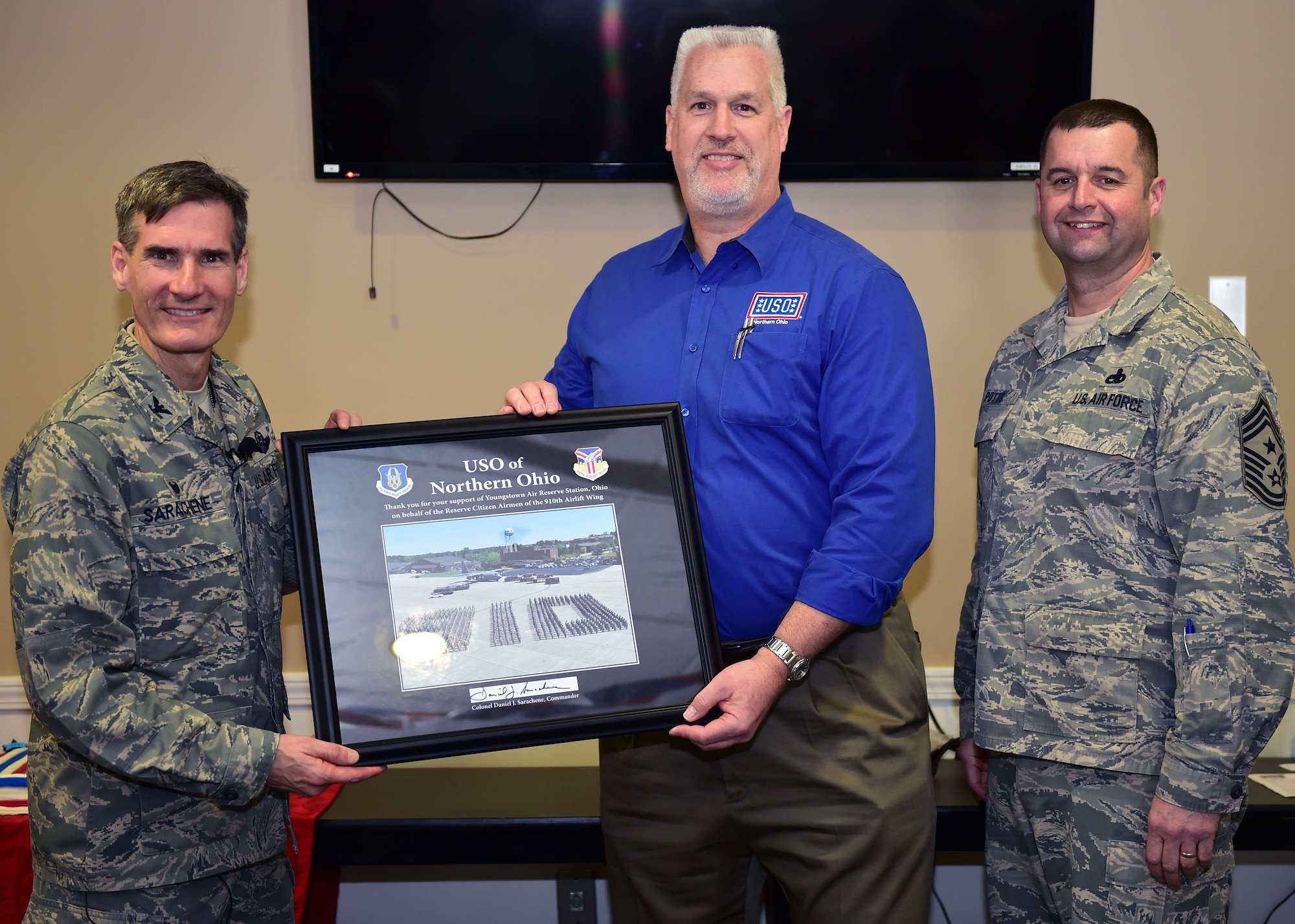 Col. Dan Sarachene, commander of the 910th Airlift Wing, and Chief Master Sgt. Robert Potts, Command Chief of the 910th Airlift Wing, present a Wing photograph to Bruce Bille, executive director of the USO of Northern Ohio, Feb. 11, 2018.