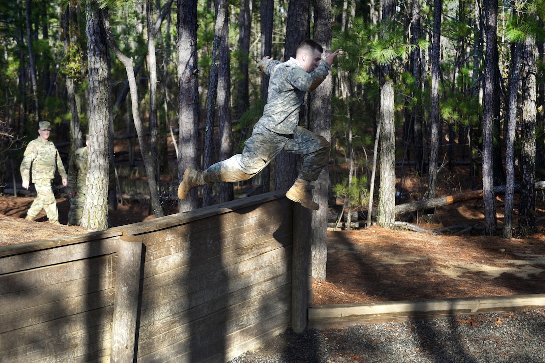 A soldier leaps off a tall wooden wall.