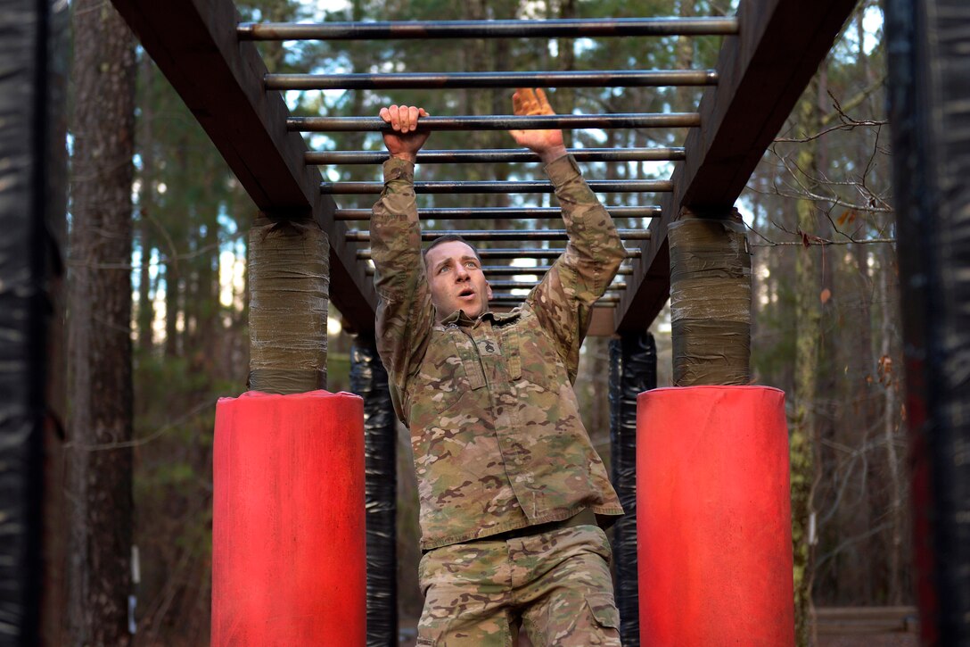 A soldier hangs from a horizontal ladder.