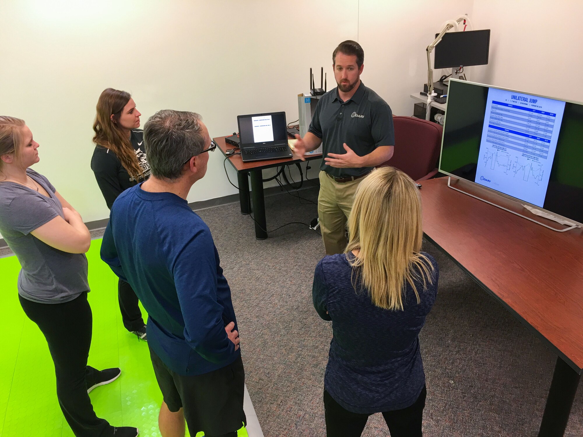 Mike Prewitt, Scientific Analytics DARImotion clinical manager, goes over a report generated by the Dynamic Athletic Research Institute 3D biomarkerless system with research physiologists and contract research athletic trainers from the United States Air Force School of Aerospace Medicine. The DARI system looks at how a person is able to move their body while performing functional tasks and can predict where an injury might occur up to two weeks before it might happen. (U.S. Air Force photo/John Harrington)