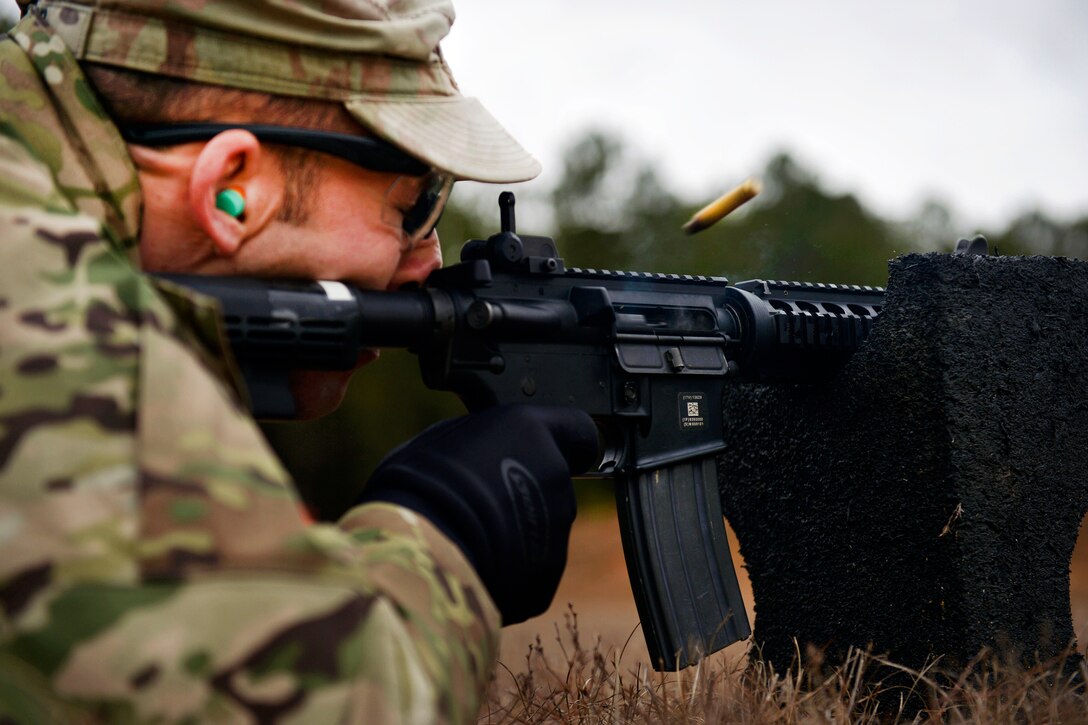 A soldier fires a rifle while laying on the ground.