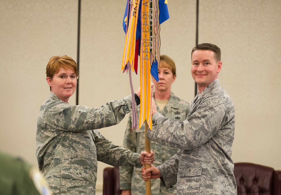 Col. Cherie Roff, 315th Mission Support Squadron commander, passes the 38th Aerial Port Squadron guide on to Maj. Jason Scnyder, new 38th APS commander, during a 315th MSG double assumption of command ceremony Feb. 11 at Joint Base Charleston, S.C. Snyder previously served as the 38th APS operations officer. (U.S. Air Force photo by 1st Lt. Rashard Coaxum)