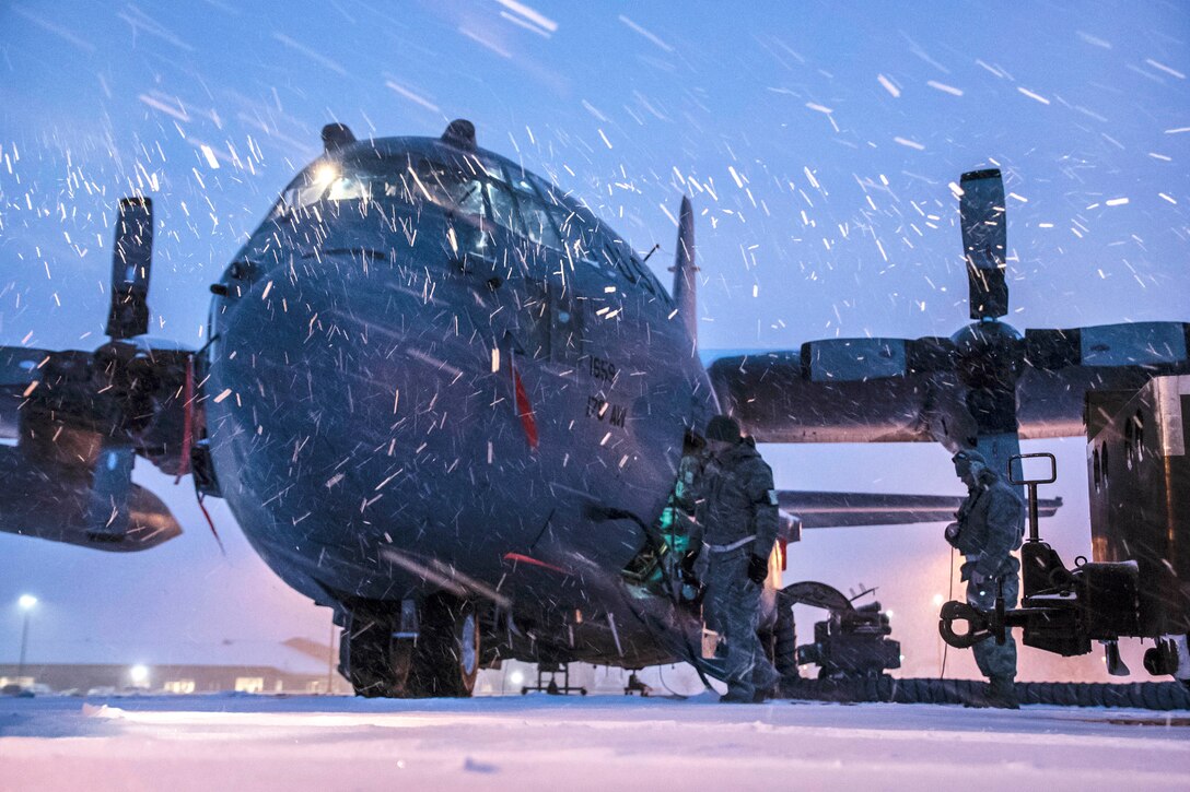 Airmen work on a Hercules aircraft during a snowstorm.