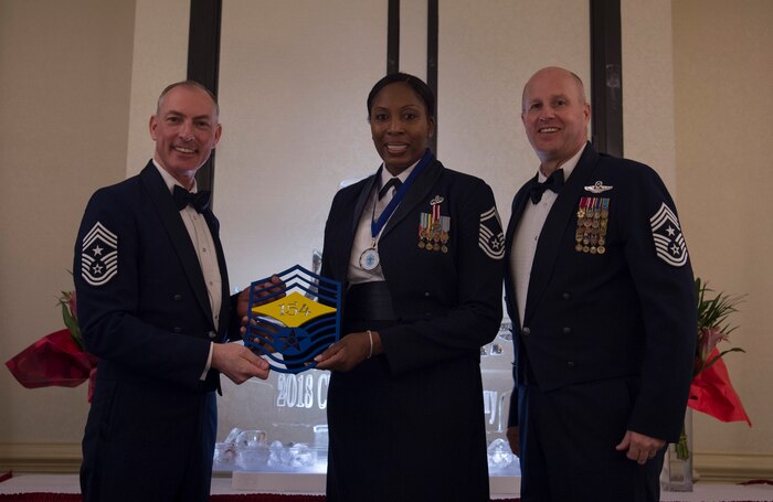Chief Master Sgt. Larry C. Williams, U.S. Air Force Expeditionary Center command chief, left, recognizes Senior Master Sgt. Carol Dorman-Gore, 628th Force Support Squadron superintendent, center, along with Chief Master Sgt. Todd Cole, 628th Air Base Wing command chief, right, during the chief master sergeant recognition ceremony at the Charleston Club Feb. 10, 2018.