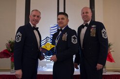Chief Master Sgt. Larry C. Williams, U.S. Air Force Expeditionary Center command chief, left, recognizes and Senior Master Sgt. Anthony Foster, 628th Contracting Squadron superintendent, center, along with Chief Master Sgt. Todd Cole, 628th Air Base Wing command chief, right, during the chief master sergeant recognition ceremony at the Charleston Club Feb. 10, 2018.