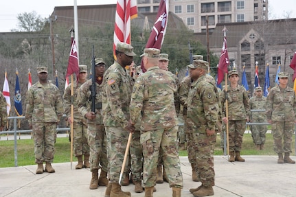 Col. Lee Freeman, commander of Brooke Army Medical Center's Troop Command, passes the guidon to incoming Command Sgt. Maj. Deonn R. Cannon during a change of responsibility ceremony at the Joint Base San Antonio-Fort Sam Houston's Army Medical Department museum amphitheater as outgoing Command Sgt. Maj. Roderick Batiste looks on Feb. 9.