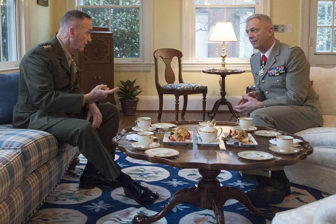 Marine Corps Gen. Joe Dunford sits on a couch and talks with his French counterpart, sitting across from him.