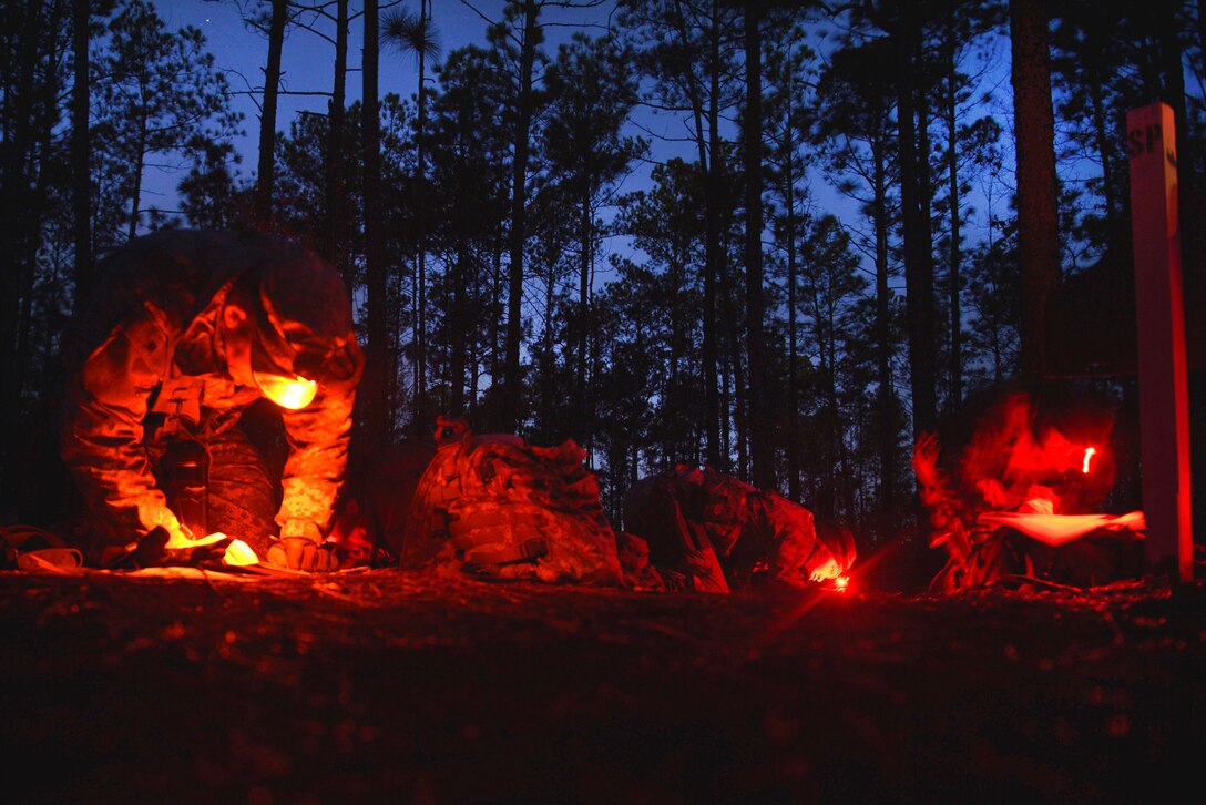 U.S. and German army soldiers use flashlights to read documents.