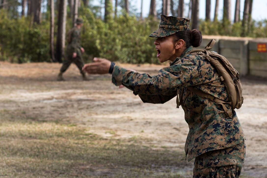 A Marine makes a hand gesture while she yells.