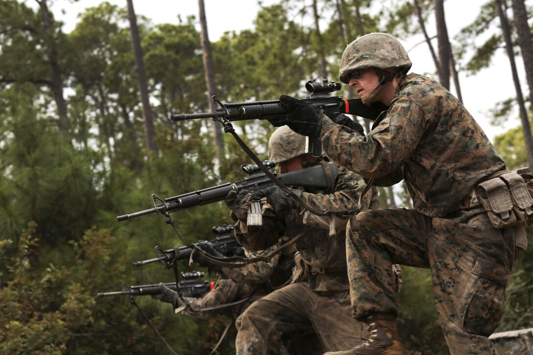 Marines aim rifles while forming a line.