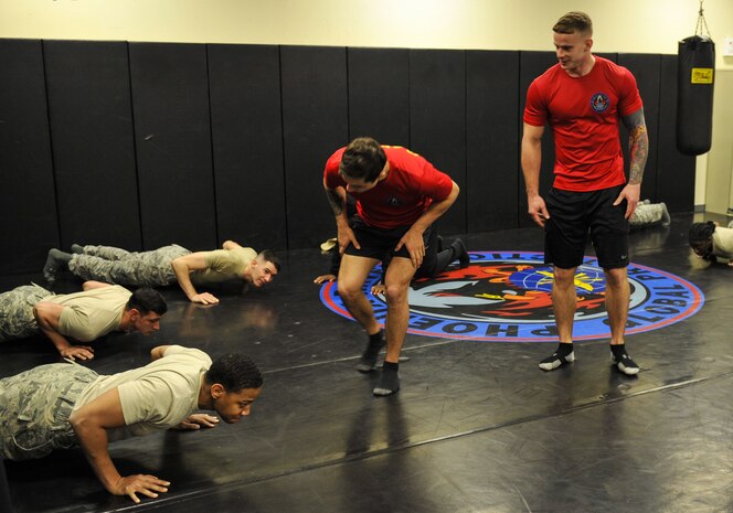 Staff Sgt. George Carty, center, 628th Security Forces Squadron Phoenix Raven and Senior Airman Cody Linday, right, 628th SFS Phoenix Raven, motivate candidates during the push-up portion of a physical training exercise Jan. 31, 2018, at Joint Base Charleston, S.C.
