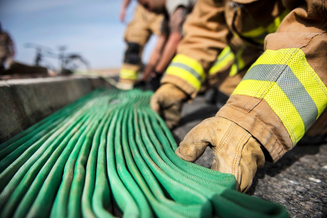 Air Force firefighters inspect fire hoses before stowing them away during a coalition emergency response exercise.