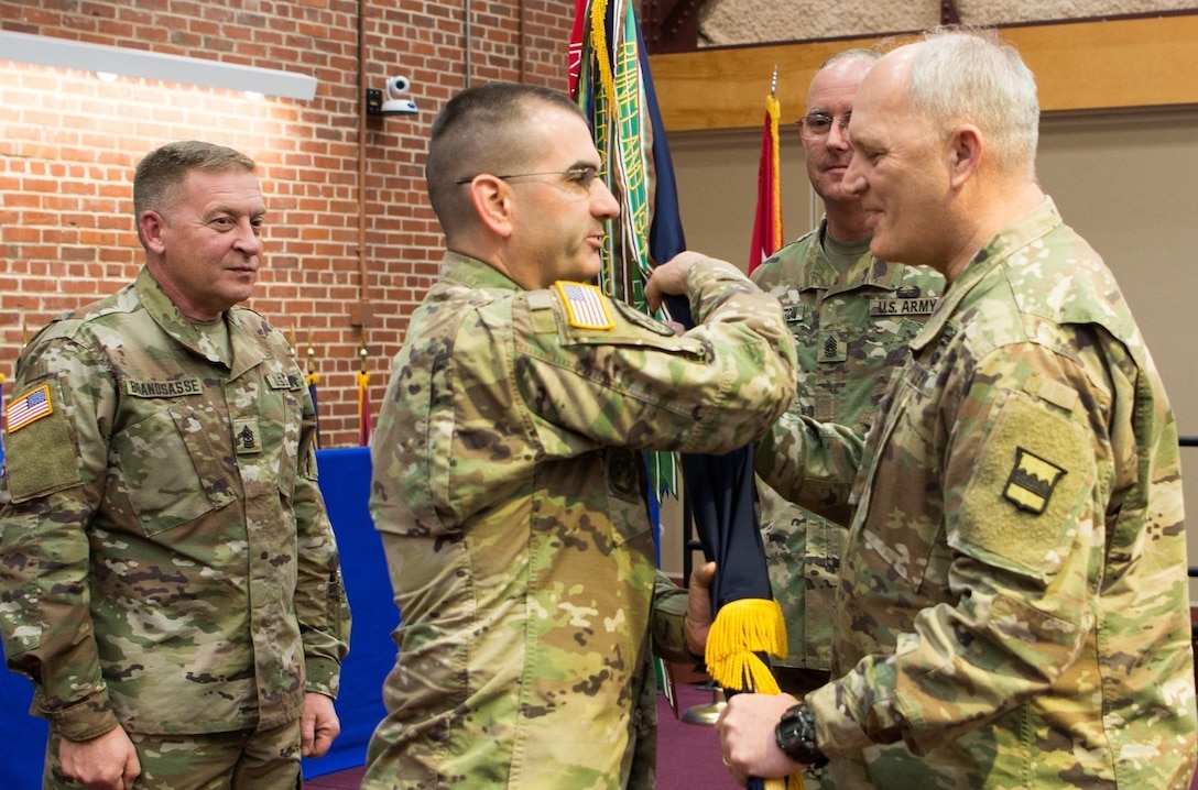 (Right) Maj. Gen. Bruce Hackett, commander of the 80th Training Command, passes the unit's guidon to Command Sgt. Maj. Dennis Thomas at the 80th's change of responsibility ceremony held at the Defense Supply Center Richmond, Virginia, during the 80th TC Commander's Readiness Workshop Feb. 8, 2018.  Sgt. Maj. Gerald Brandsasse (far left) looks on. (U.S. Army Reserve Photo by Maj. Addie Leonhardt)