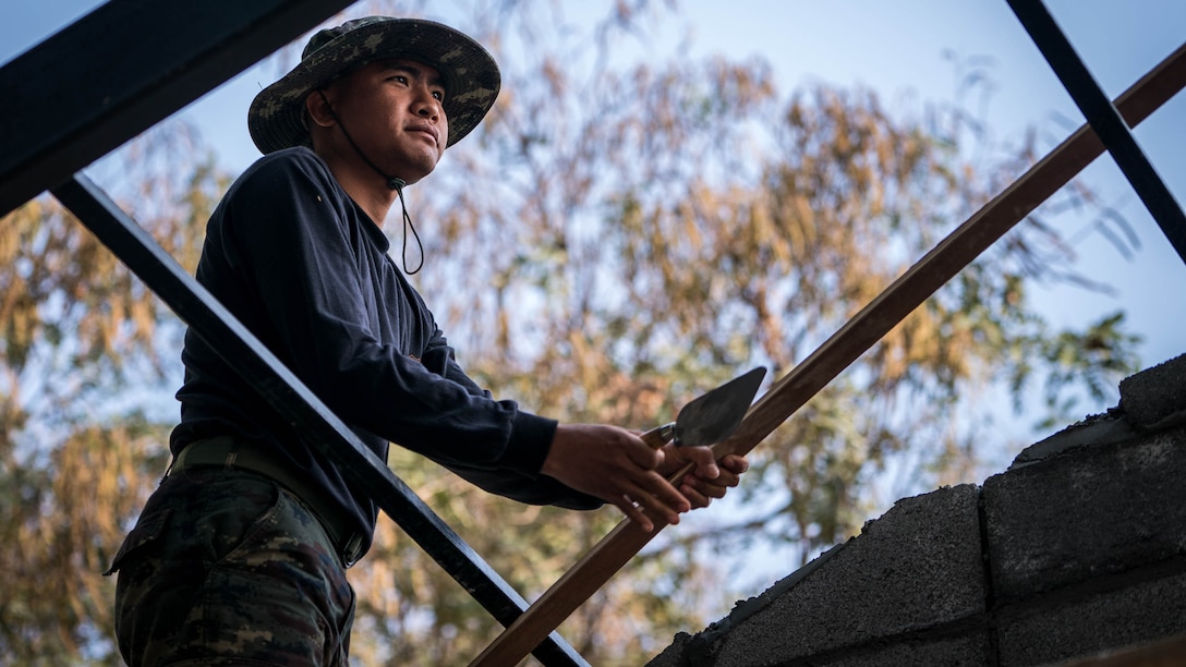 Royal Thai Army Pvt. Peradeet Thumnamal moves a piece of wood in order to smooth stucco for a school building in support of Exercise Cobra Gold 2018 at Nonphipadungkhitwittaya School in Korat, Kingdom of Thailand, Feb. 7, 2018. Thumnamal is an engineer with Engineering Combat Unit, and is a native of Udon Thani, Thailand. Humanitarian civic assistance projects conducted during the exercise support the needs and humanitarian interests of the Thai people. Cobra Gold 18 is an annual exercise conducted in the Kingdom of Thailand held from Feb. 13-23 with seven full participating nations.