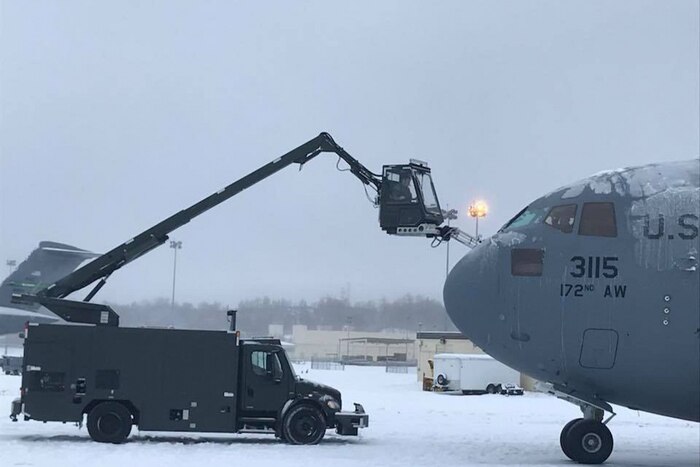 Airmen de-ice a military aircraft.