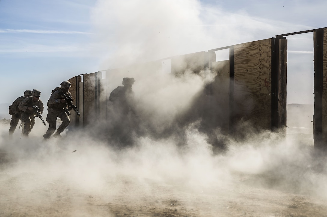 Marines participate in training to breach doors as smoke rises.