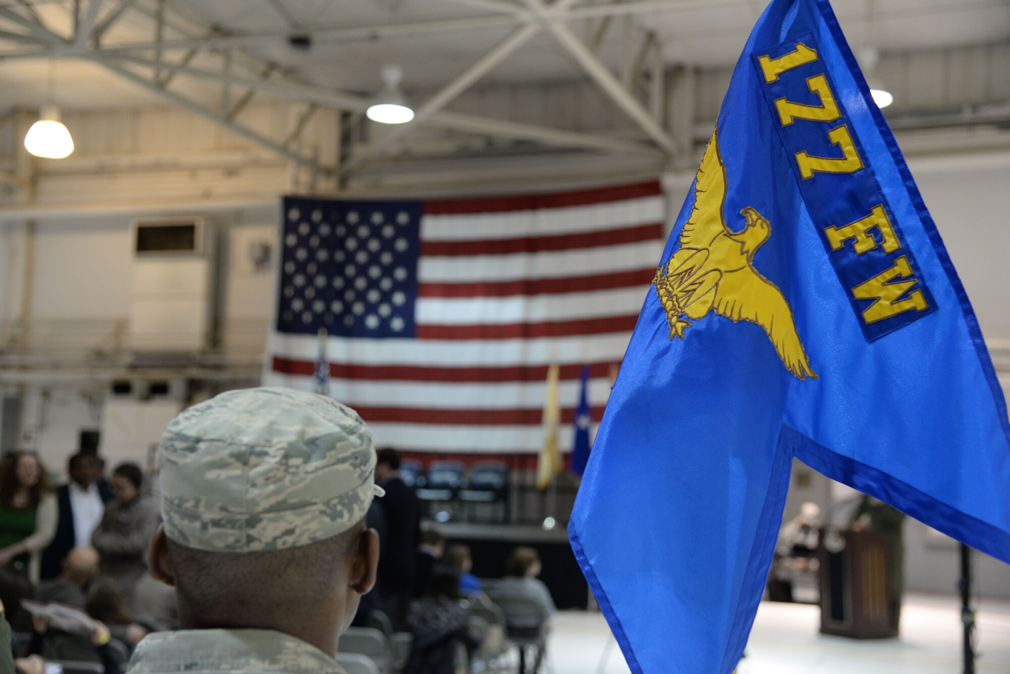 A picture of a member of the New Jersey Air National Guard's 177th Fighter Wing standing with the wing's guidon.
