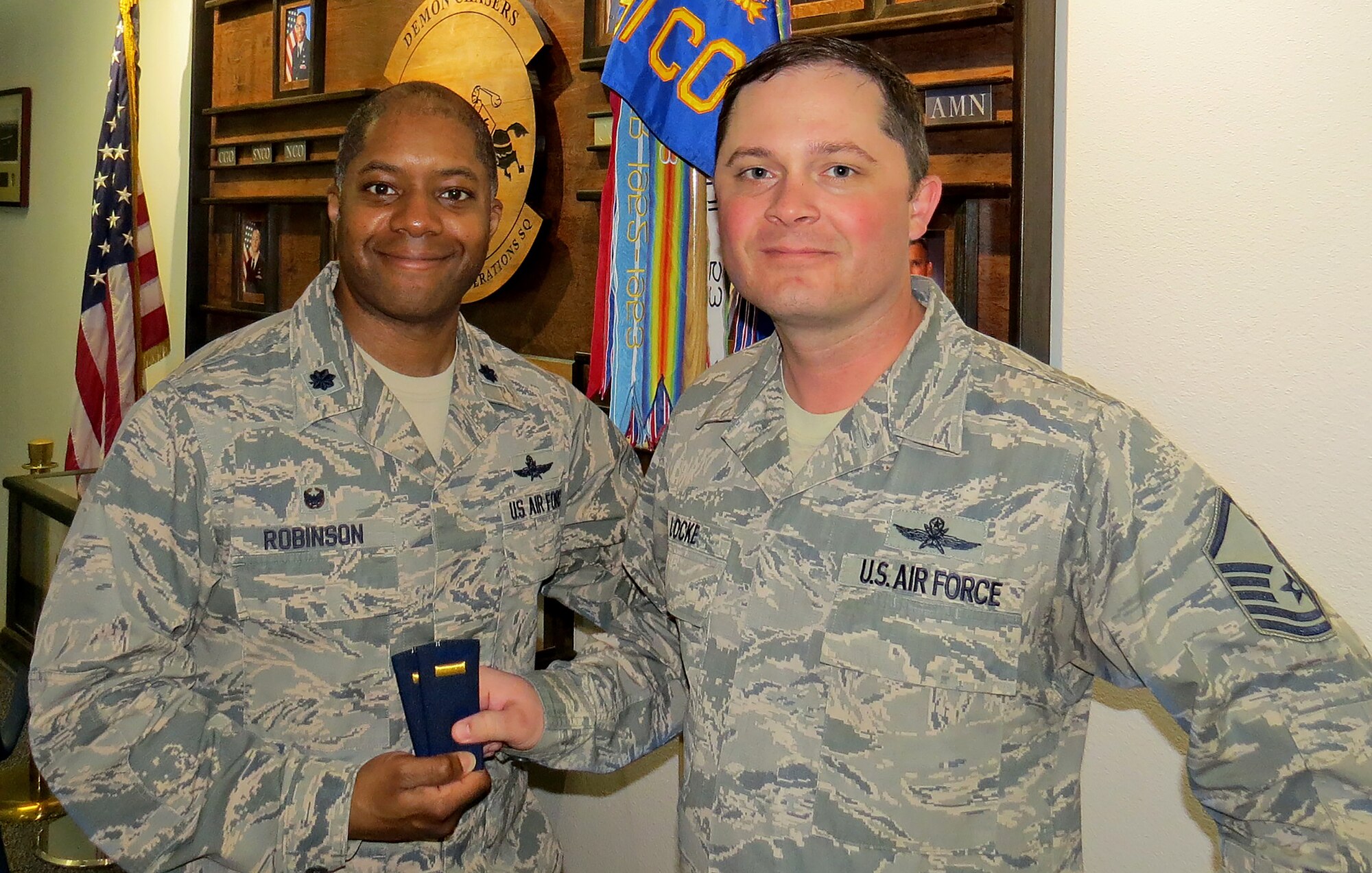 Lt. Col. Christopher Robinson, 91st Cyberspace Operations Squadron commander, hands second lieutenant ranks to Master Sgt. Micheal Locke, 91st COS operations superintendent, to celebrate his selection as a candidate for the newly authorized cyber direct appointment program. Upon successful completion of the program, Locke will commission as a second lieutenant. (Courtesy photo)
