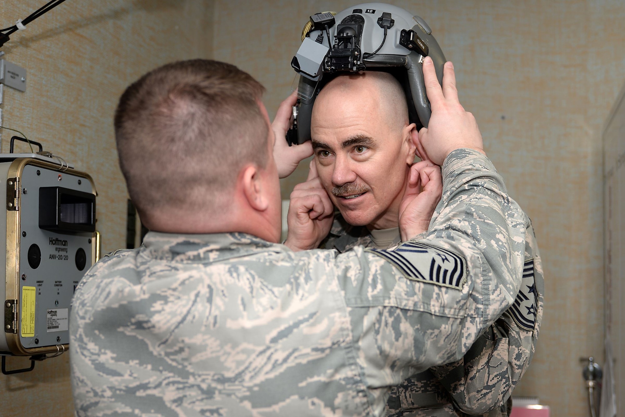 A picture of U.S. Air Force Chief Master Sgt. Jason L. Gioconda placing a Helmet Mounted Integrated Targeting System on Command Chief Master Sgt. Ronald C. Anderson, command chief master sergeant of the Air National Guard.