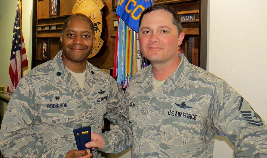 Lt. Col. Christopher Robinson, 91st Cyberspace Operations Squadron commander, hands second lieutenant ranks to Master Sgt. Micheal Locke, 91st COS operations superintendent, to celebrate his selection as a candidate for the newly authorized cyber direct appointment program. Upon successful completion of the program, Locke will commission as a second lieutenant.
