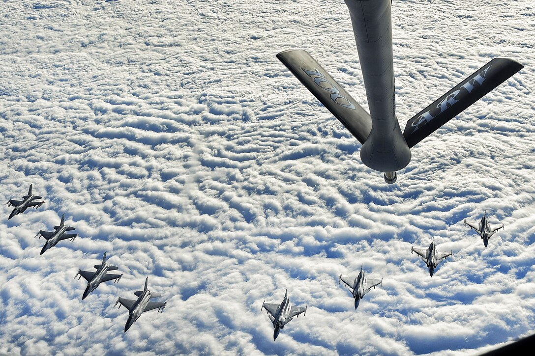 Four U.S and four Swedish aircraft fly in formation above a cloud cover.
