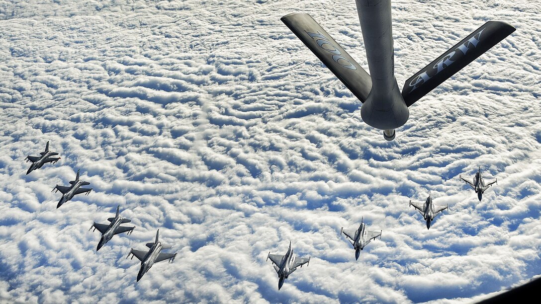 Four U.S and four Swedish aircraft fly in formation above a cloud cover.