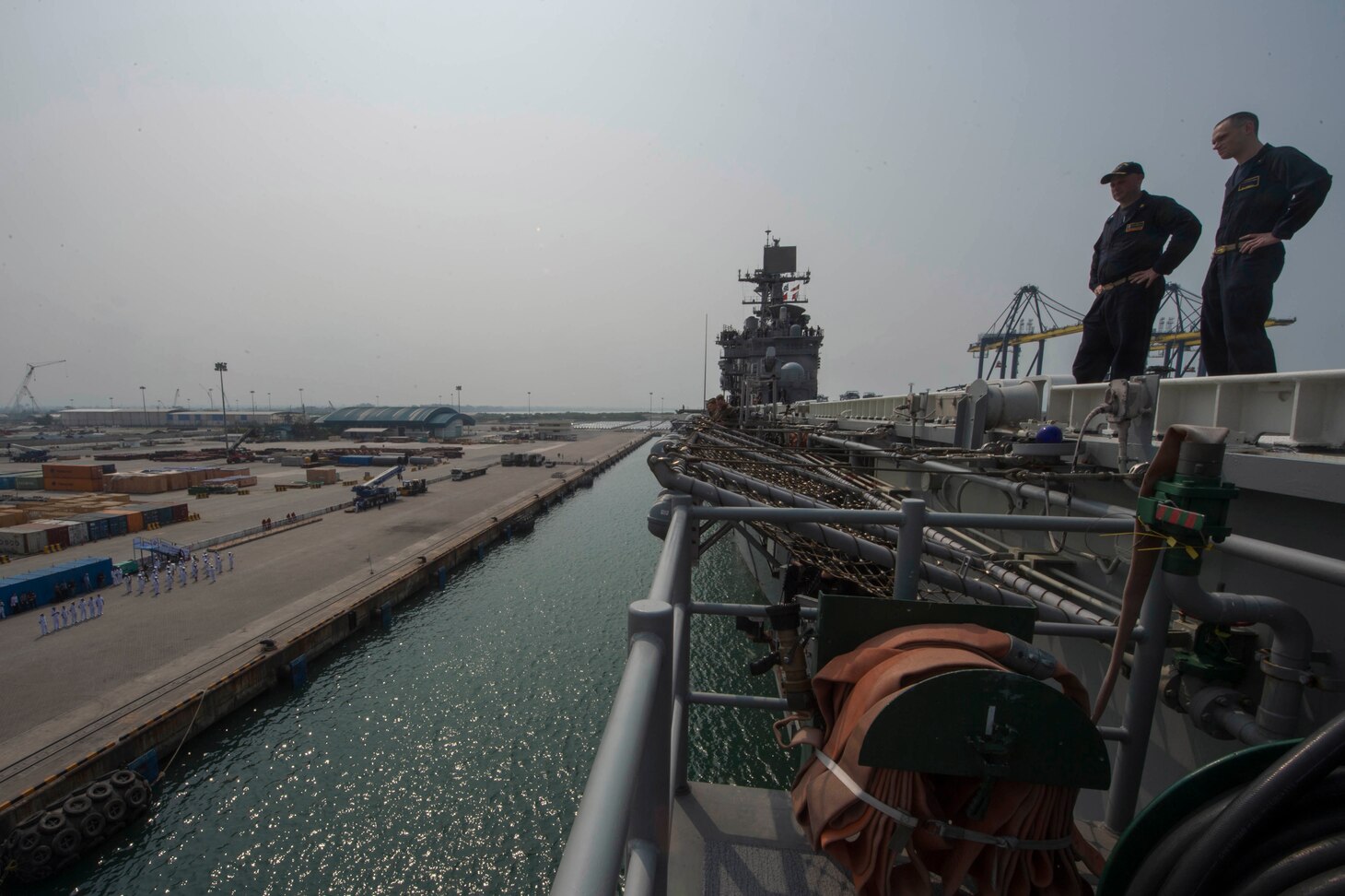 Cmdr. Keith Capper, left, supply officer of the amphibious assault ship USS Bonhomme Richard (LHD 6), and Lt. David Hammond, assistant command chaplain of Bonhomme Richard, observe Laem Chebang, Thailand, as the ship arrives for a scheduled port visit before beginning Cobra Gold 2018 (CG18). Cobra Gold, a Thai-U.S. co-sponsored exercise in its 37th iteration, is designed to advance regional security and ensure effective responses to regional crises by bringing together a robust multinational force to address shared goals and security commitments in the Indo-Asia-Pacific region. Bonhomme Richard is operating in the Indo-Asia-Pacific region as part of a regularly scheduled patrol and provides a rapid-response capability in the event of a regional contingency or natural disaster.